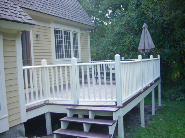 Cape Cod house painter show gold house with white trim and white deck railings with mahagony deck